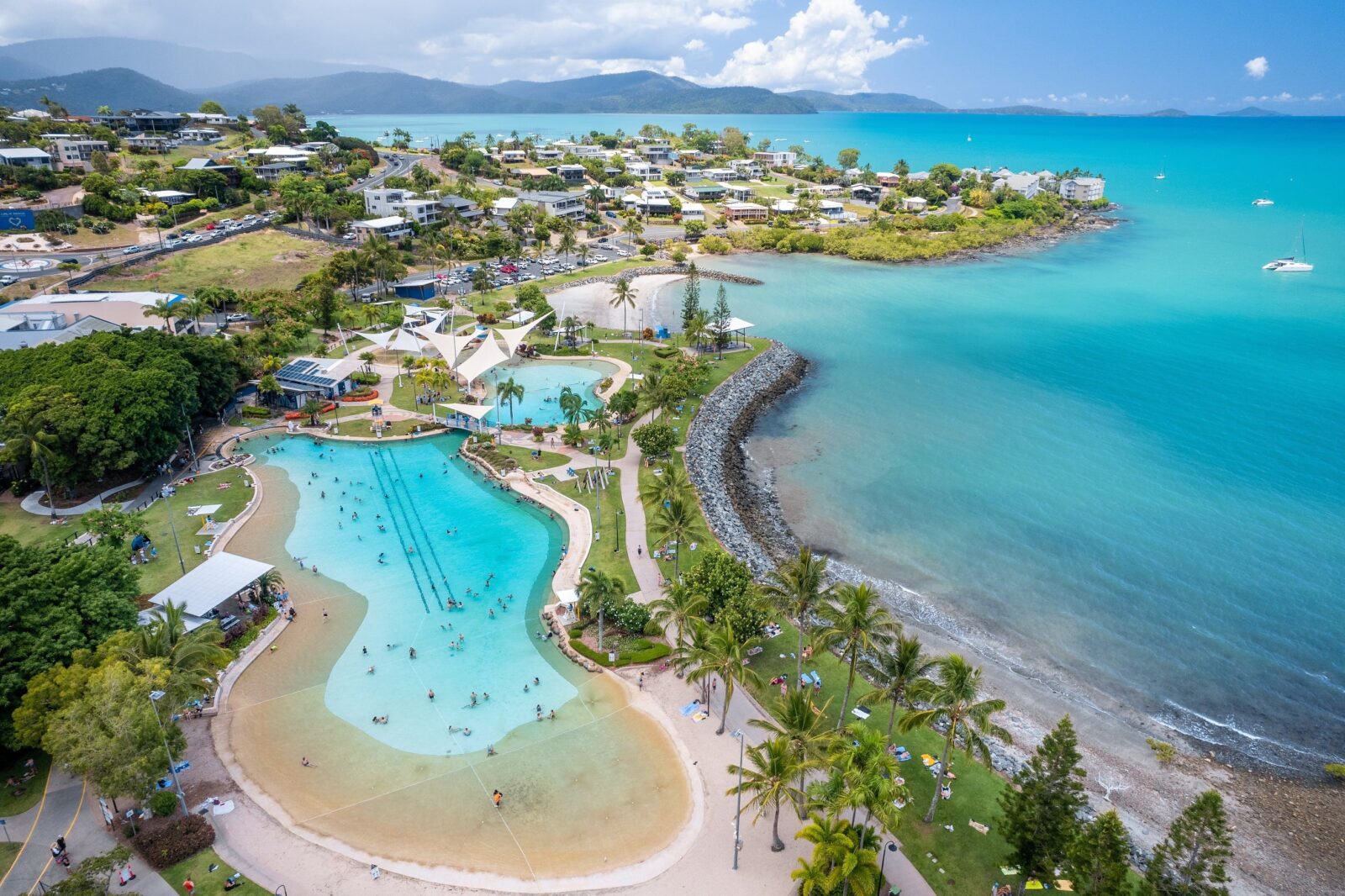 Aerial photo of Airlie Beach Lagoon with houses, beach and blue ocean surrounding