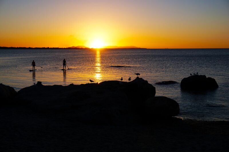 Paddle boarders with the sun setting over Grays Bay Bowen