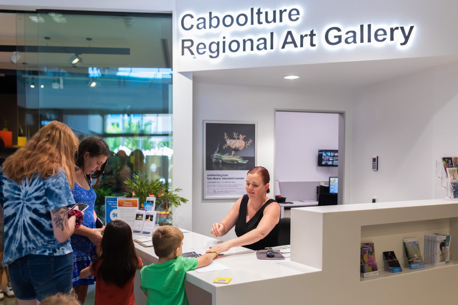 Family interacting with Caboolture Regional Art Gallery team at front desk