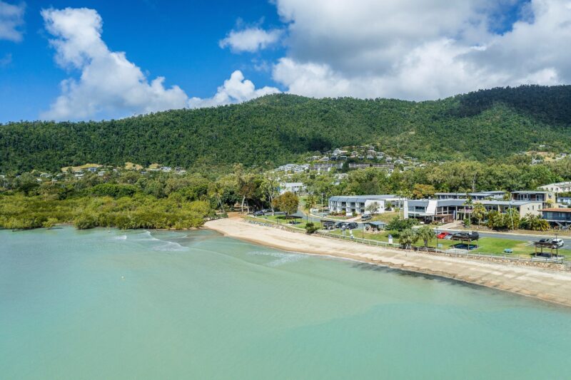 Aerial view of Cannonvale Beach with foreshore shops and offices, beach and picnic areas