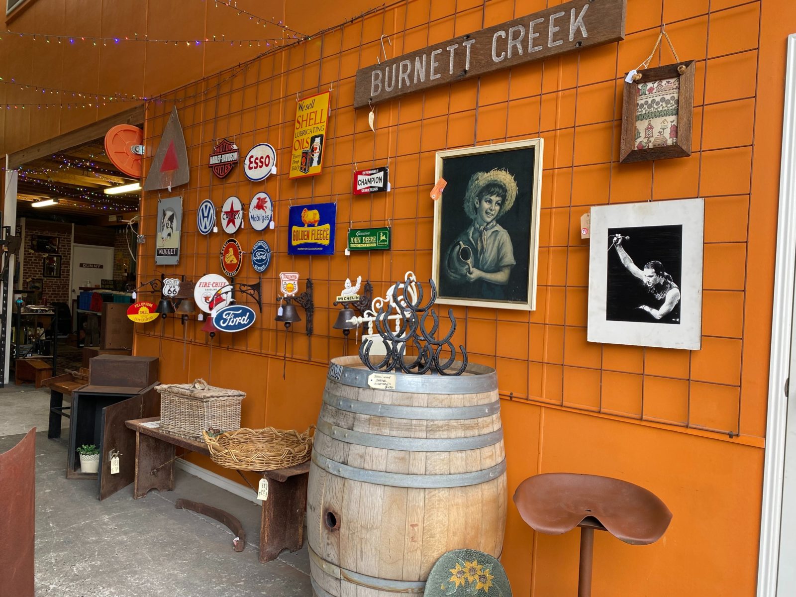 A wide photo of an orange painted wall with rustic items hanging on display