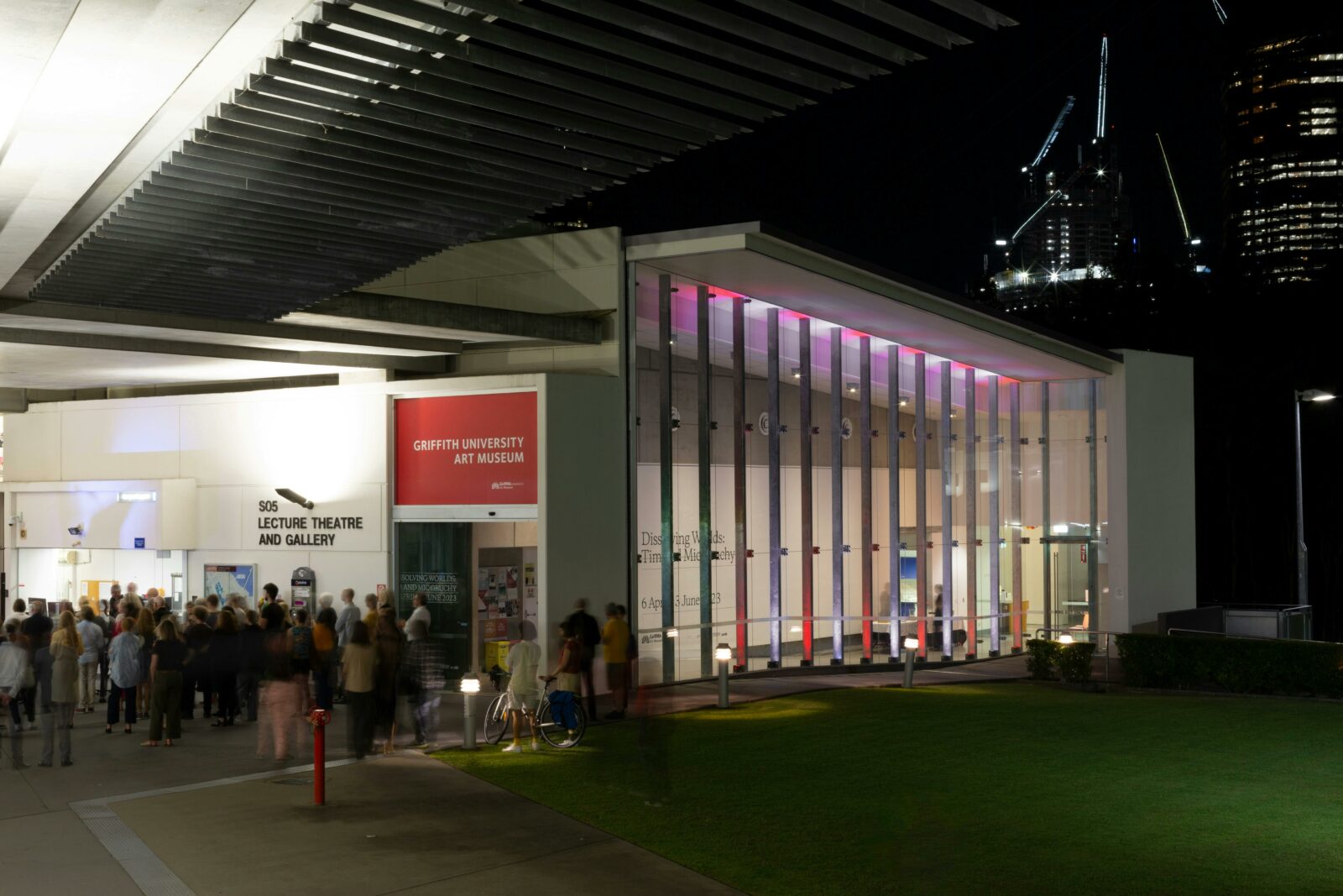 Exterior view of Griffith University Art Museum at nigh, with a large crowd