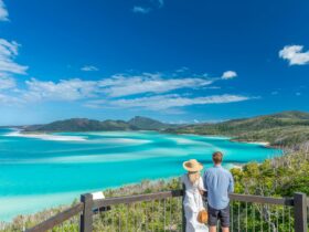 A woman and a man looking over the swirling sands and turquoise waters of the inlet from a lookout