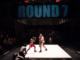 two actors create a boxing scene on stage with a full audience