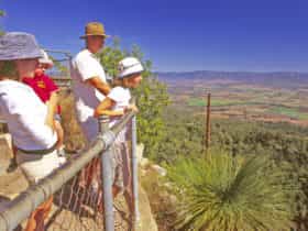 Young family at high lookout with views over bushland, farmland and mountains.