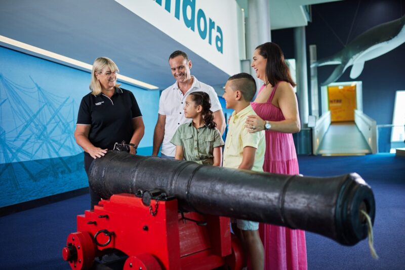 Family of 4 talking with museum guide next to a cannon