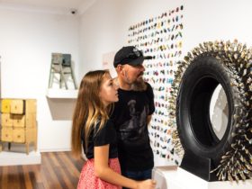 Lady and man looking at a wall-mounted exhibition item