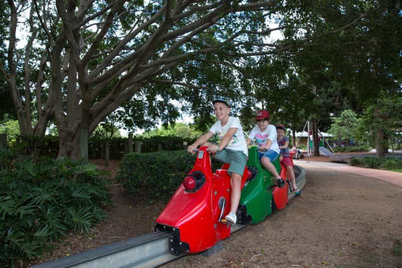 Two young boys on a pedal powered train in park
