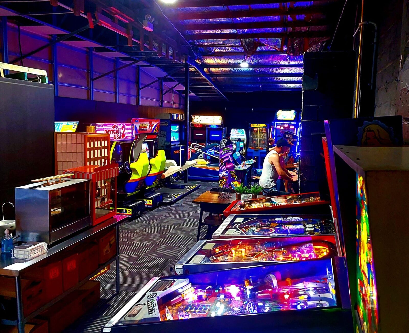 Picture showing a peek through the arcade venue. You can see pinball machines, racers, snack bar