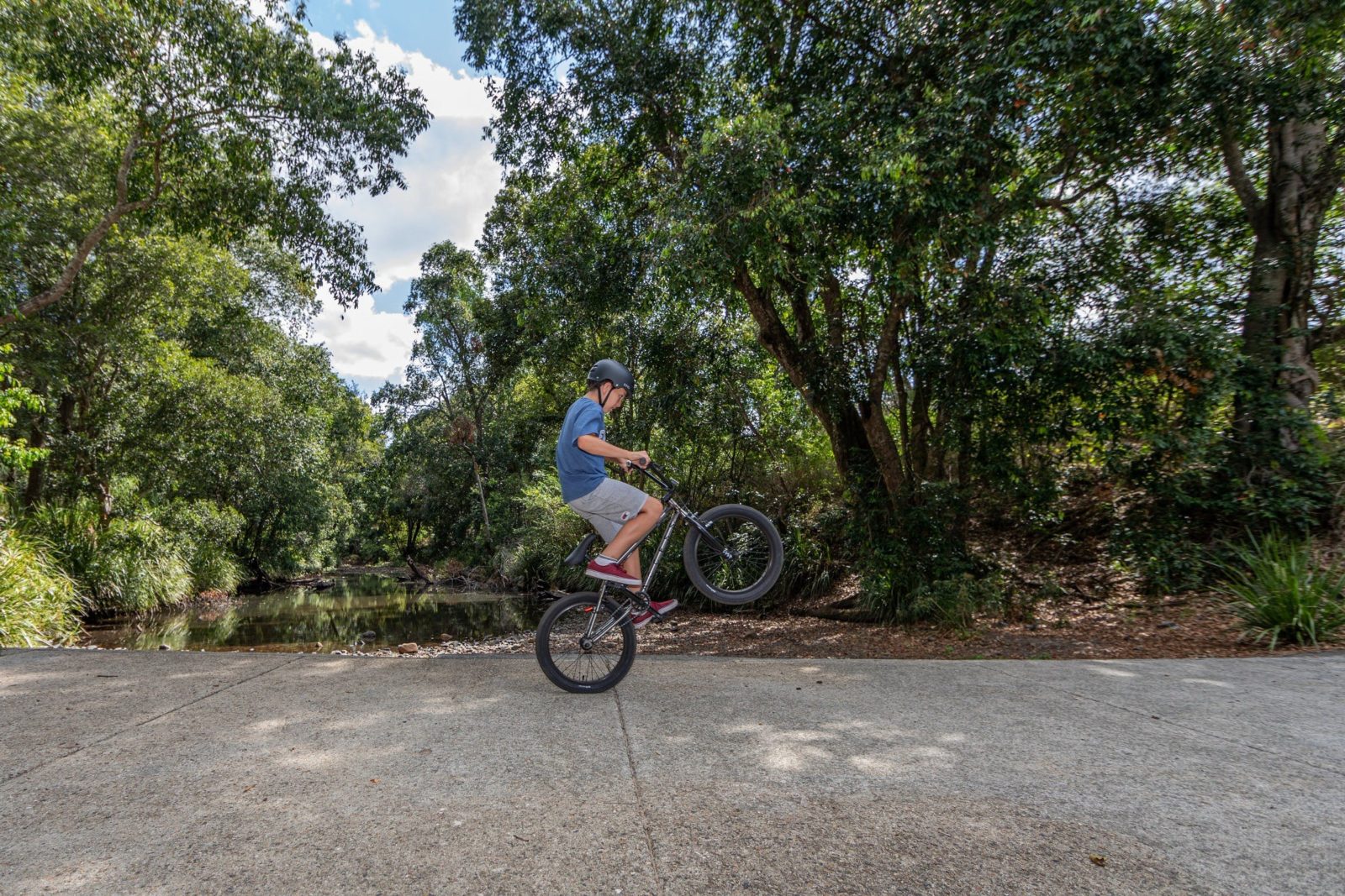 A boy doing a wheelie on his bike on the Samford Valley Rail Trail