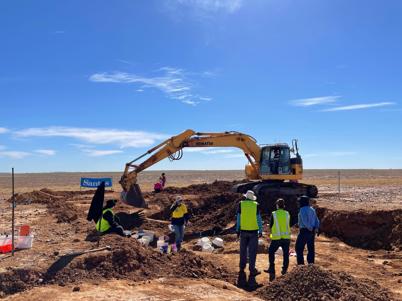 Dig site with heavy machinery and participants working in the dirt