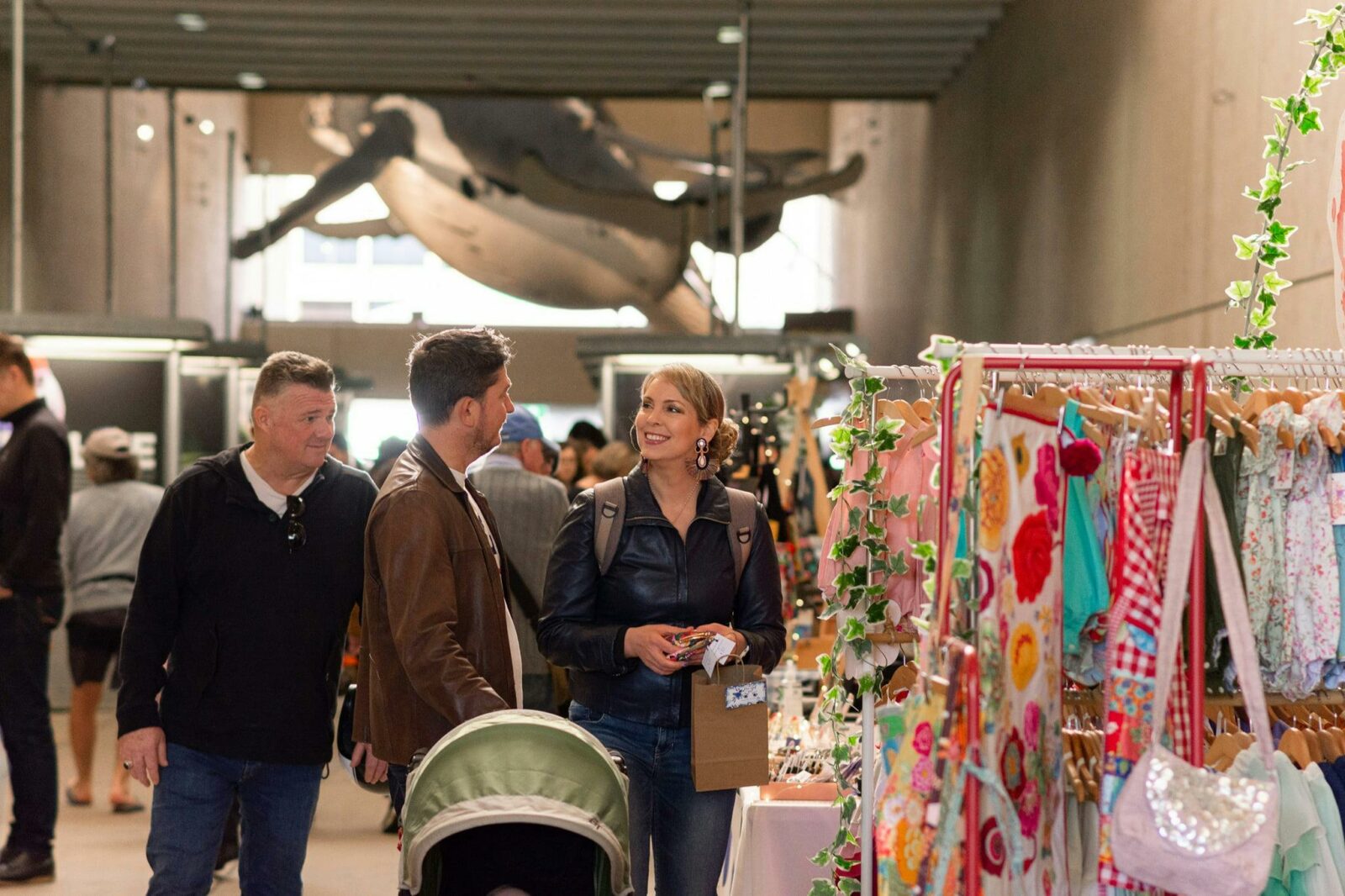 A Family smiling and shopping with the Flying whale installation in the background