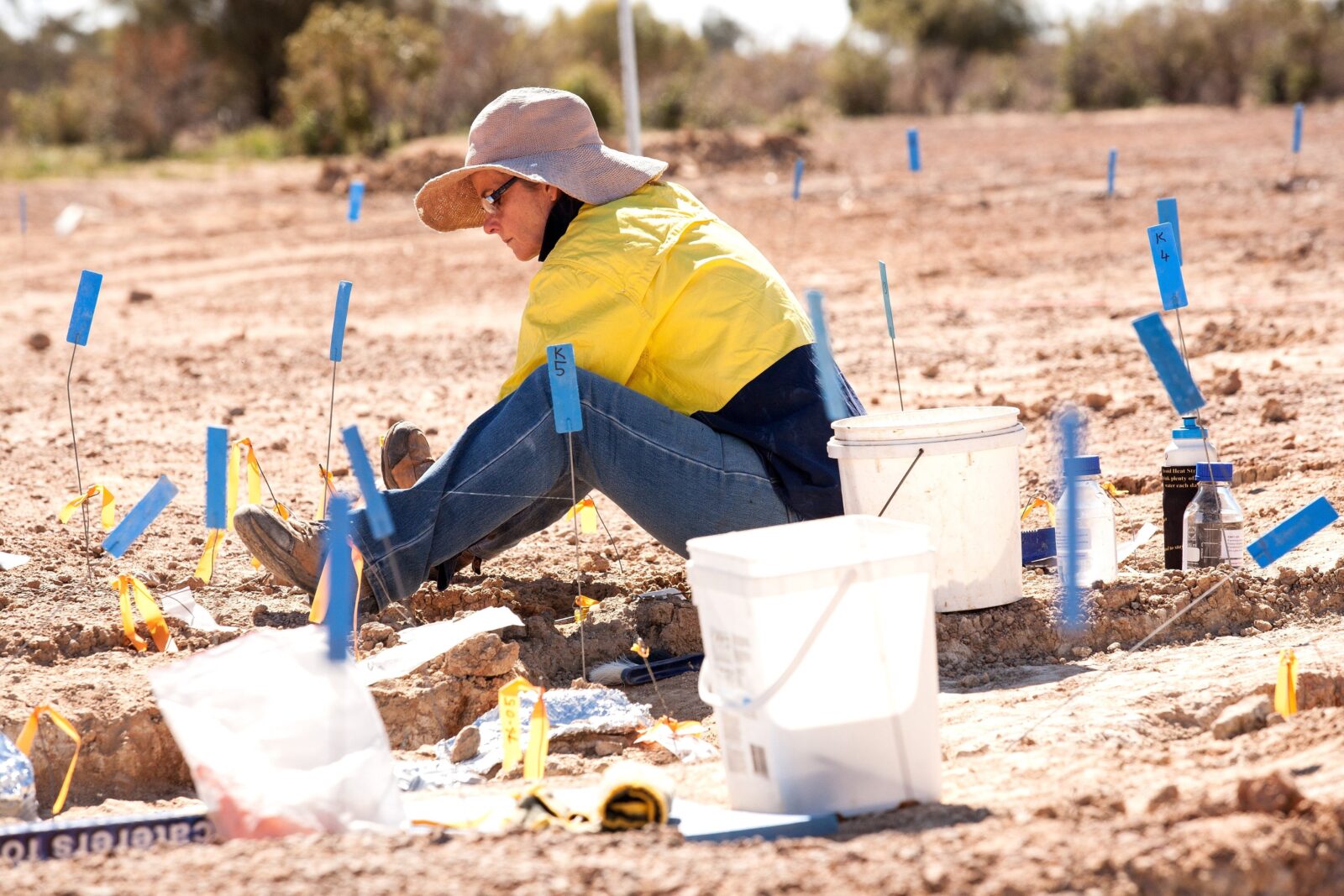 Person sitting on the ground digging in the middle of sectioned work area