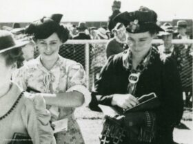 Historic image, black and white. Two ladies in 1950s fashion attire entering the racecourse.