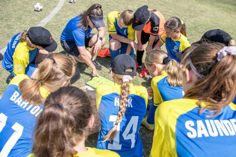 group of female football players in a huddle talking