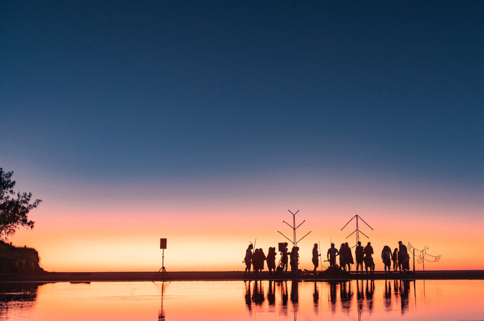 Performers gathered on a beach at dawn
