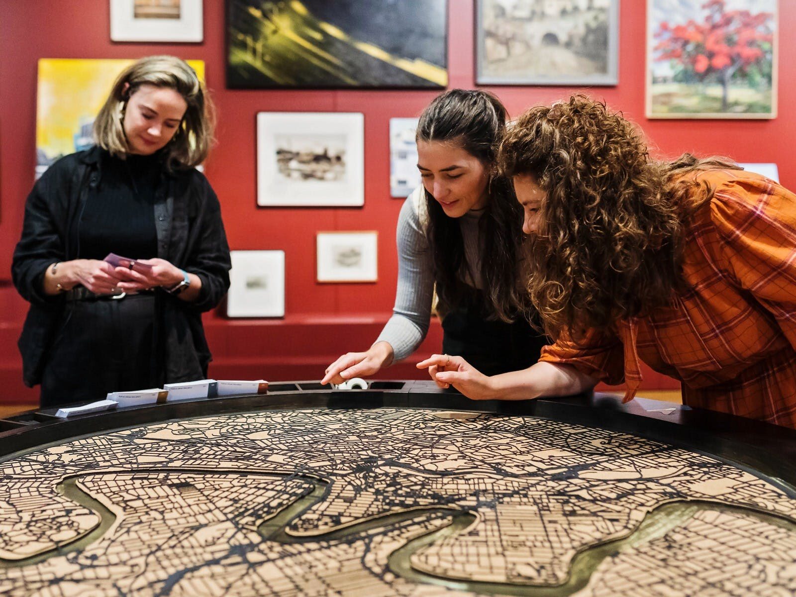 Three people stand around a table inlaid with a laser-cut map artwork of Brisbane.