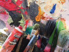 Paint brushes and paint on an artist's palette.