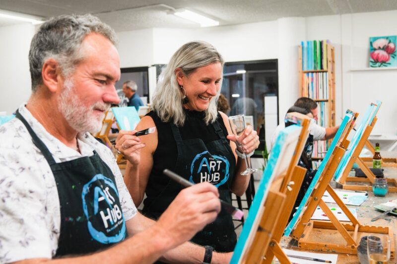 A couple enjoying a glass of wine and painting at The Art Hub Paint and Sip Studio.