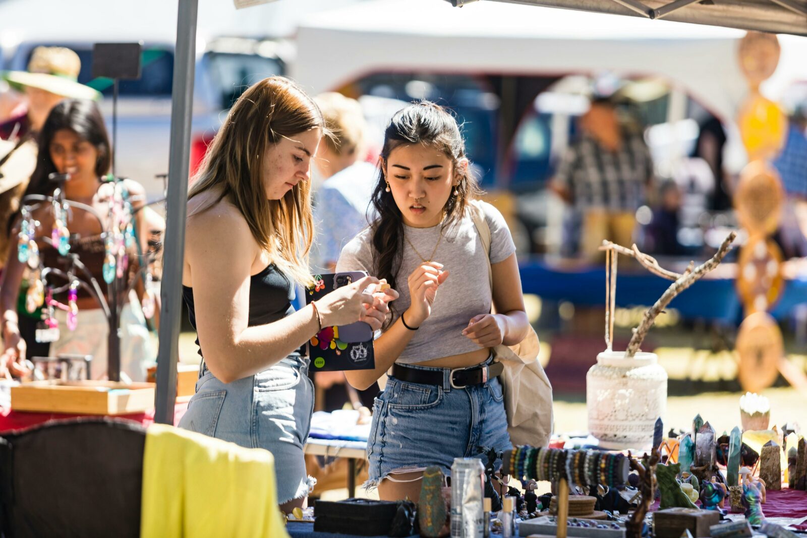 two young women looking at market items