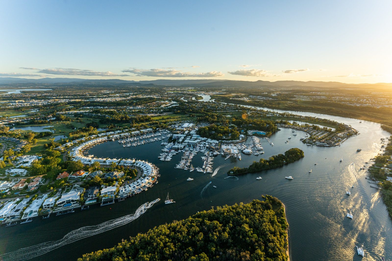 Ariel view of Sanctuary Cove, a harbour filled with white boats and surrounded by greenery.