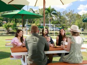 Group of people sitting at a picnic bench outside at the bowls club enjoying each others company