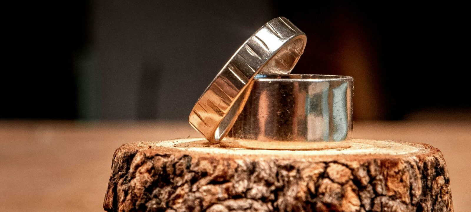 A set of sterling silver rings, stacked on top of each other, sitting on top of a piece of wood.