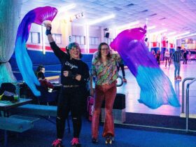 Two people waving colourful silks near a skate rink