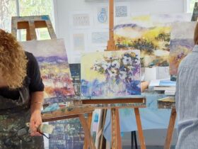 two artists working on paintings resting on easels in the background. Soft tonal colouring