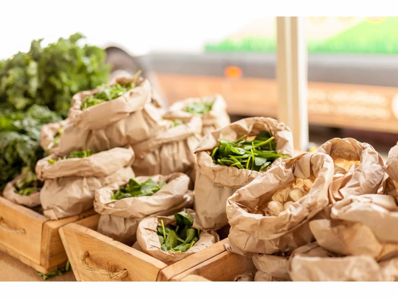 Bags of fresh spinach and mushrooms on display at a market stall