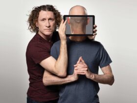 Two men one holding a screen at the other persons neck