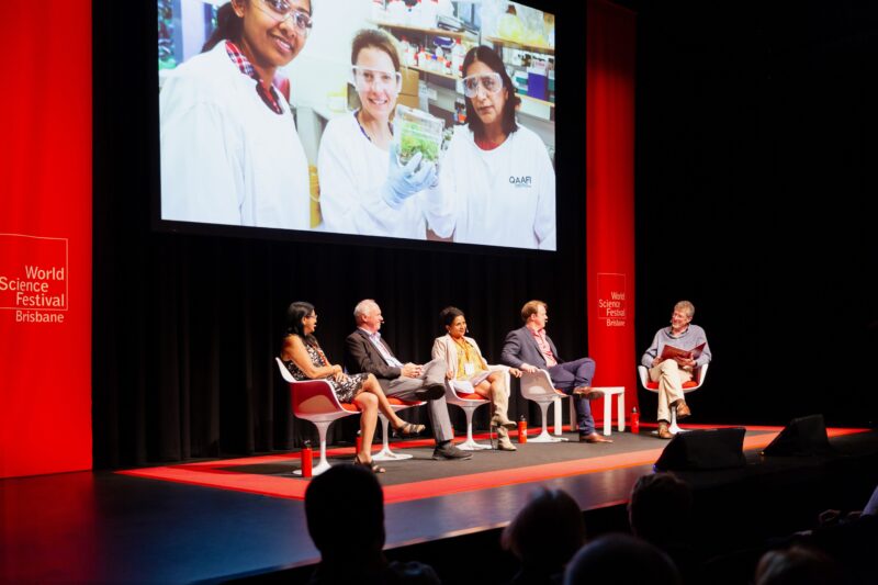 Four scientists sit on a stage looking towards a moderator at the festival.