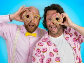Two men holding a doughnut to their eye