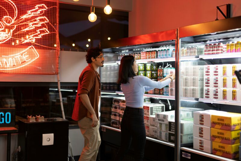 A couple standing in-front of a shop beer fridge