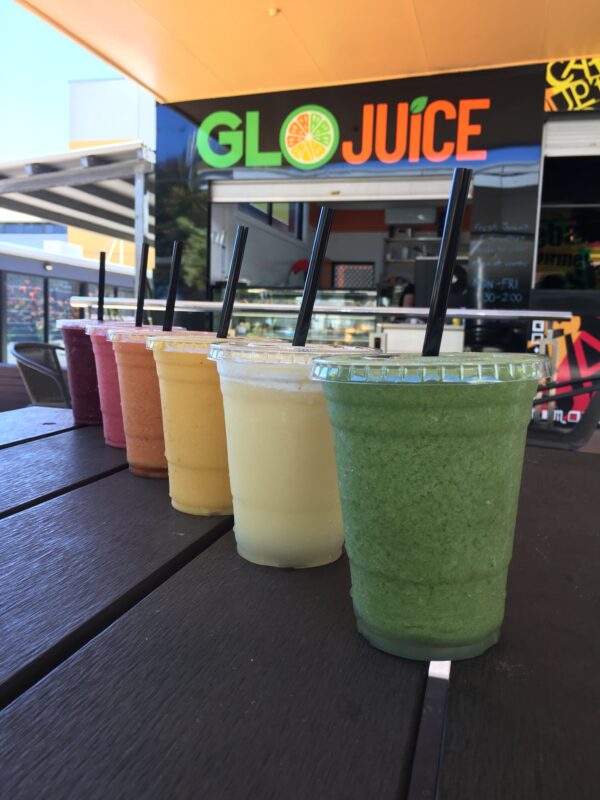 Colourful range of smoothies sat on a table in front of Glo Juice.