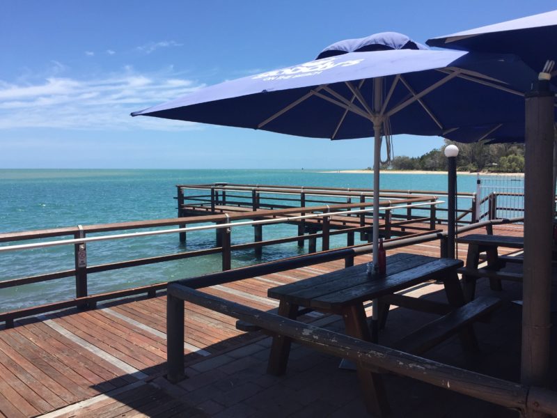 photo showing large market umbrellas shading tables at front of Goody's on the Beach with seaview be