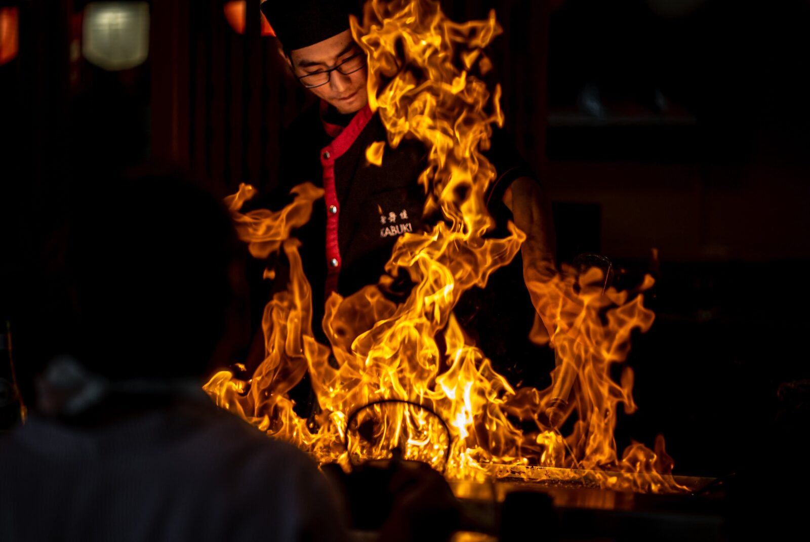Teppanyaki chef behind a flame on a grill