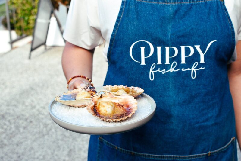A chef from Pippy Fish Café serves a plate of grilled miso scallops.