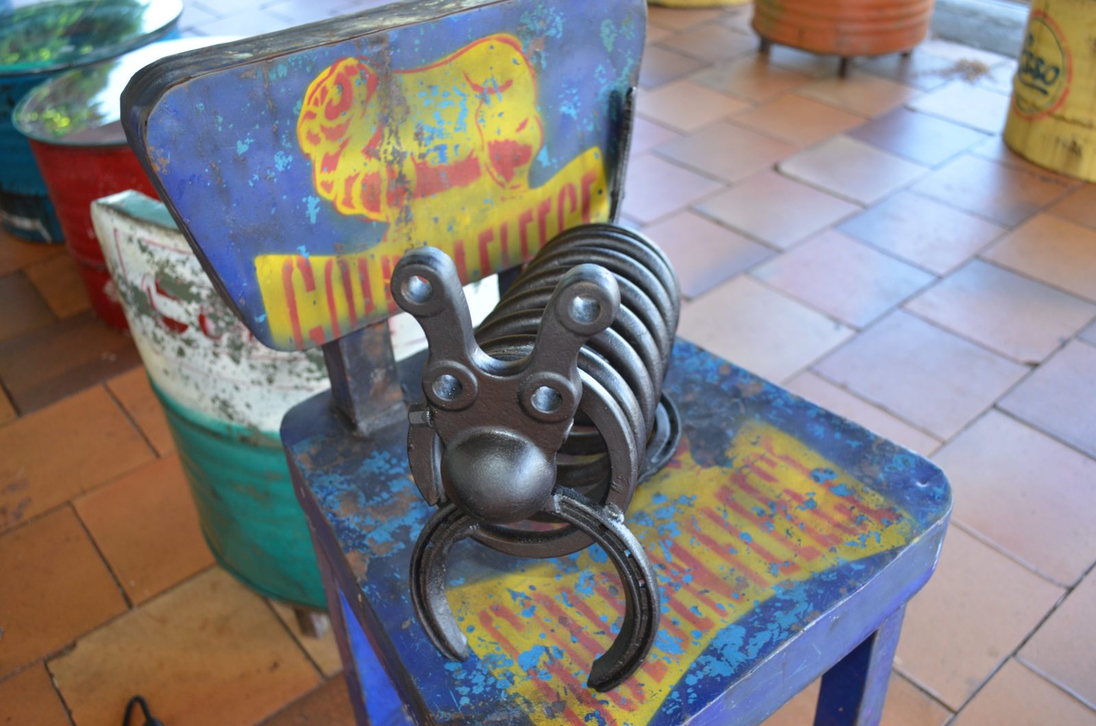 photo of a hand made steel art piece sitting on a tin chair outside Retro Espresso Cafe Tiaor