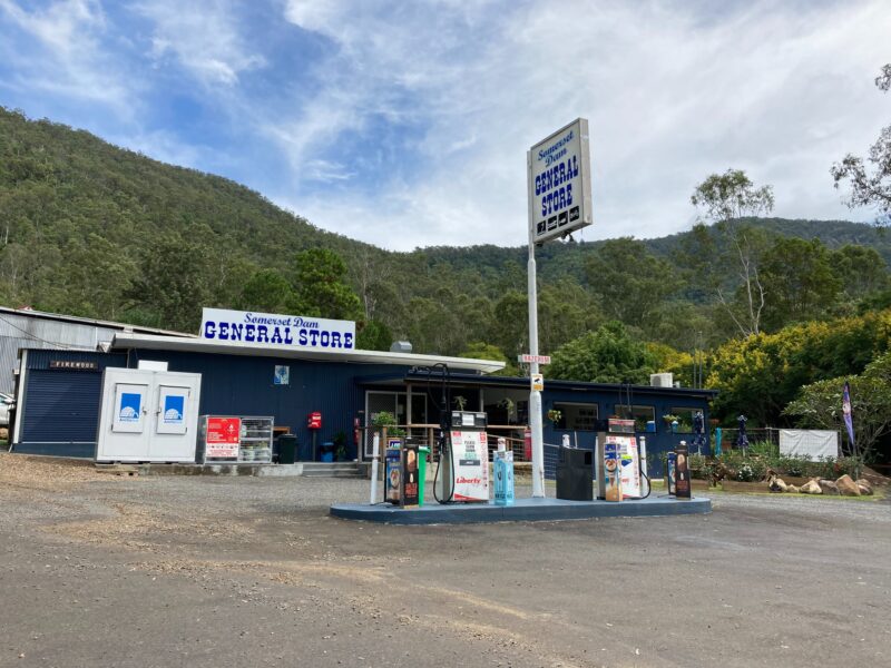 Photograph of the Somerset Dam General Store - blue building with 2 petrol pumps in the fore ground