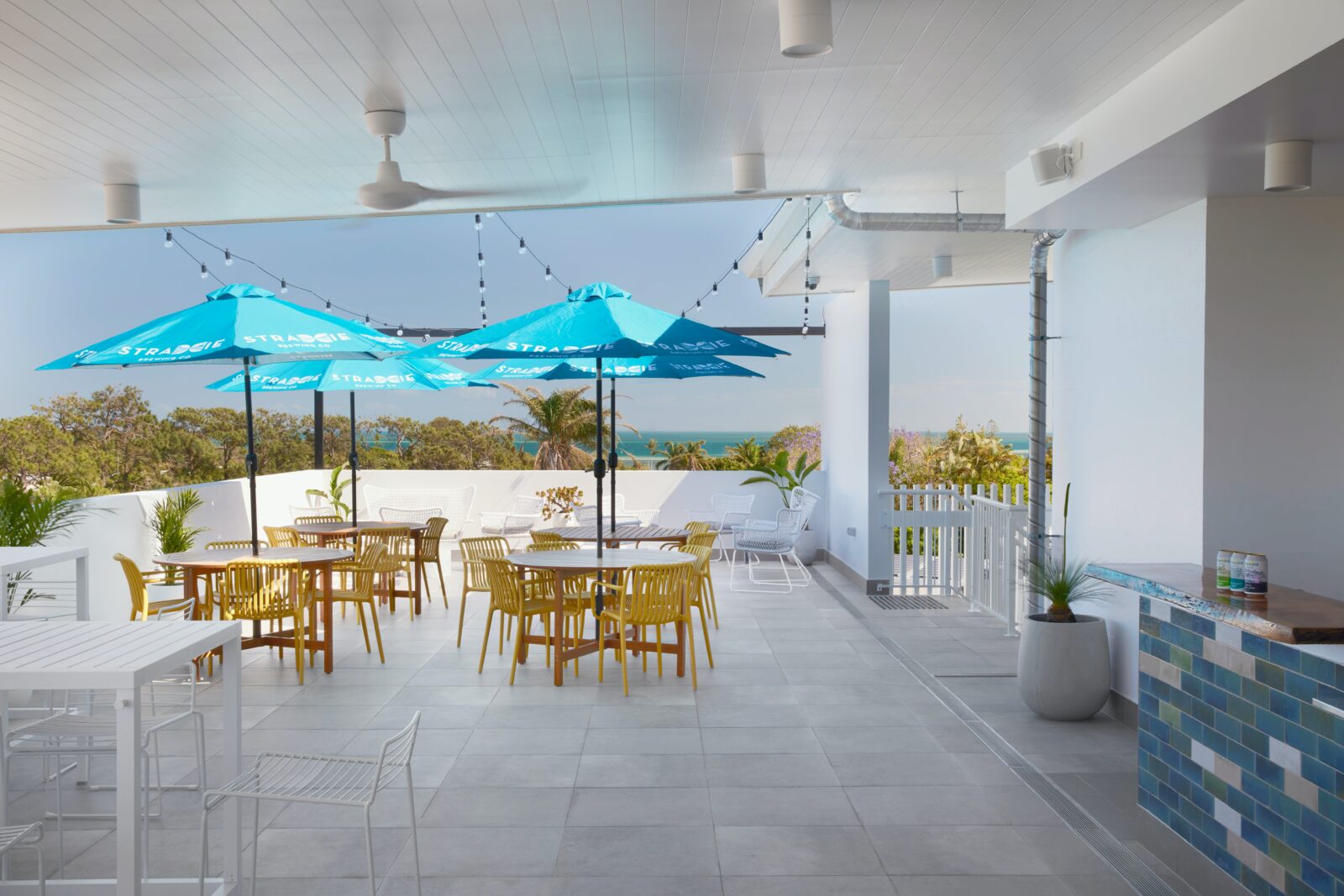 Rooftop Deck with low set tables covered with umbrellas, and views of the water and greenery