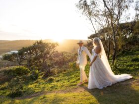 Newly wed couple walking together with the sun setting in the background