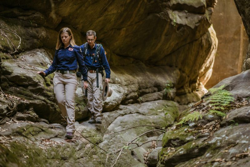 Two tour guides walking through a sandstone slot canyon at Carnarvon Gorge.