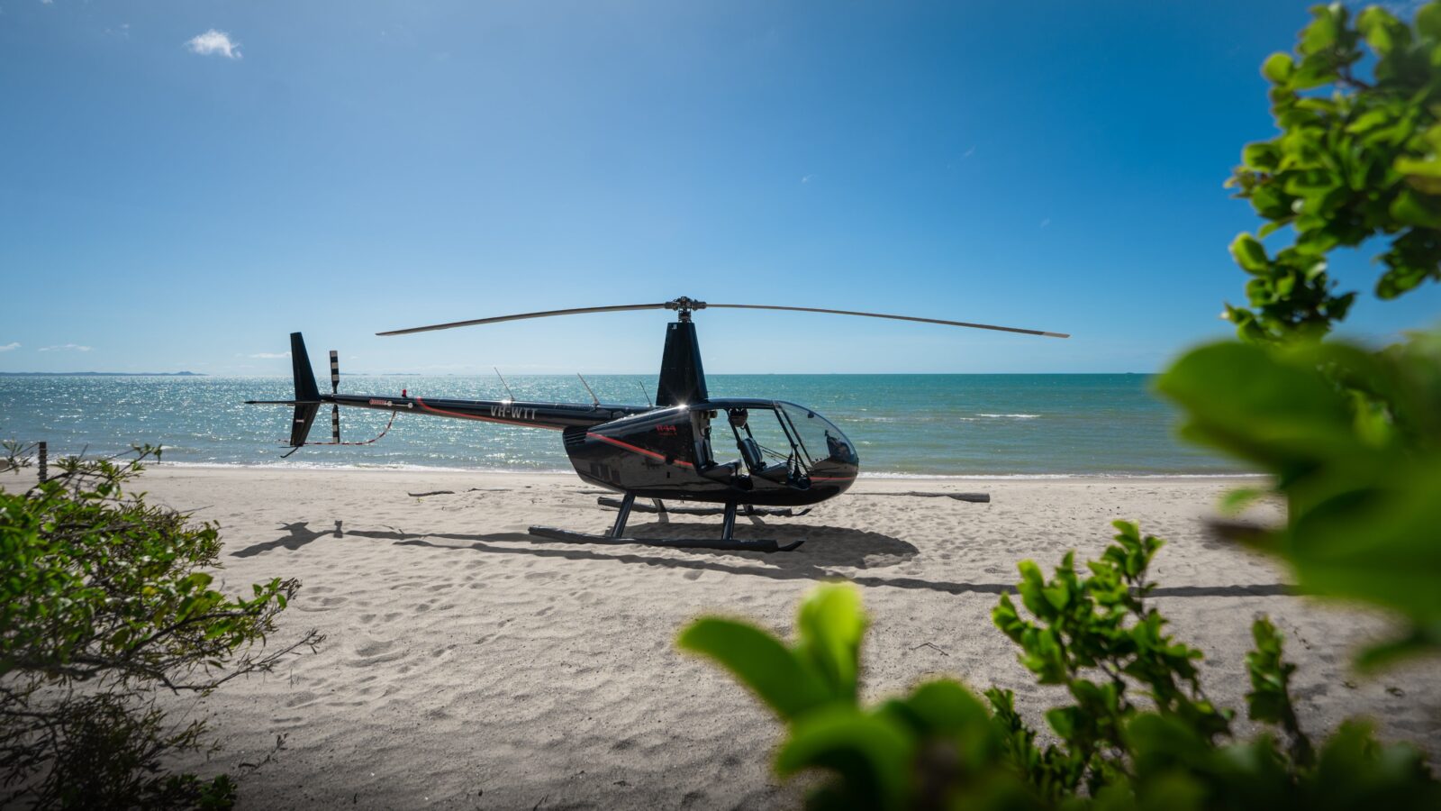 Coastal Rotors helicopter parked on Punsand Bay Beach, Cape York, ready to take flight.