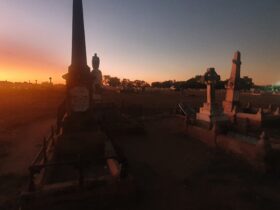 Charters Towers Cemetery with a few grave statues and thesun setting in distance