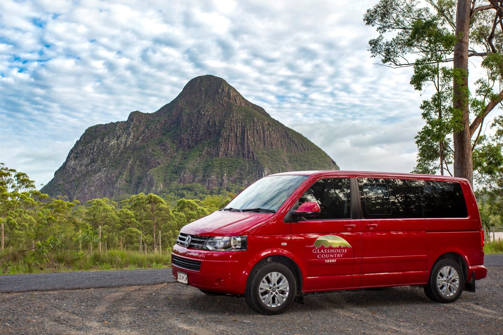 Image show the Glasshouse Country Tours bus with a view of Mt Beerwah in the background