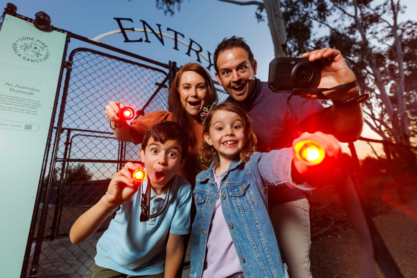 Young family with red-light torches at the entry gates to Nocturnal