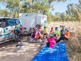Guests sitting on stools next to Mulga Bicycle Tours trailer