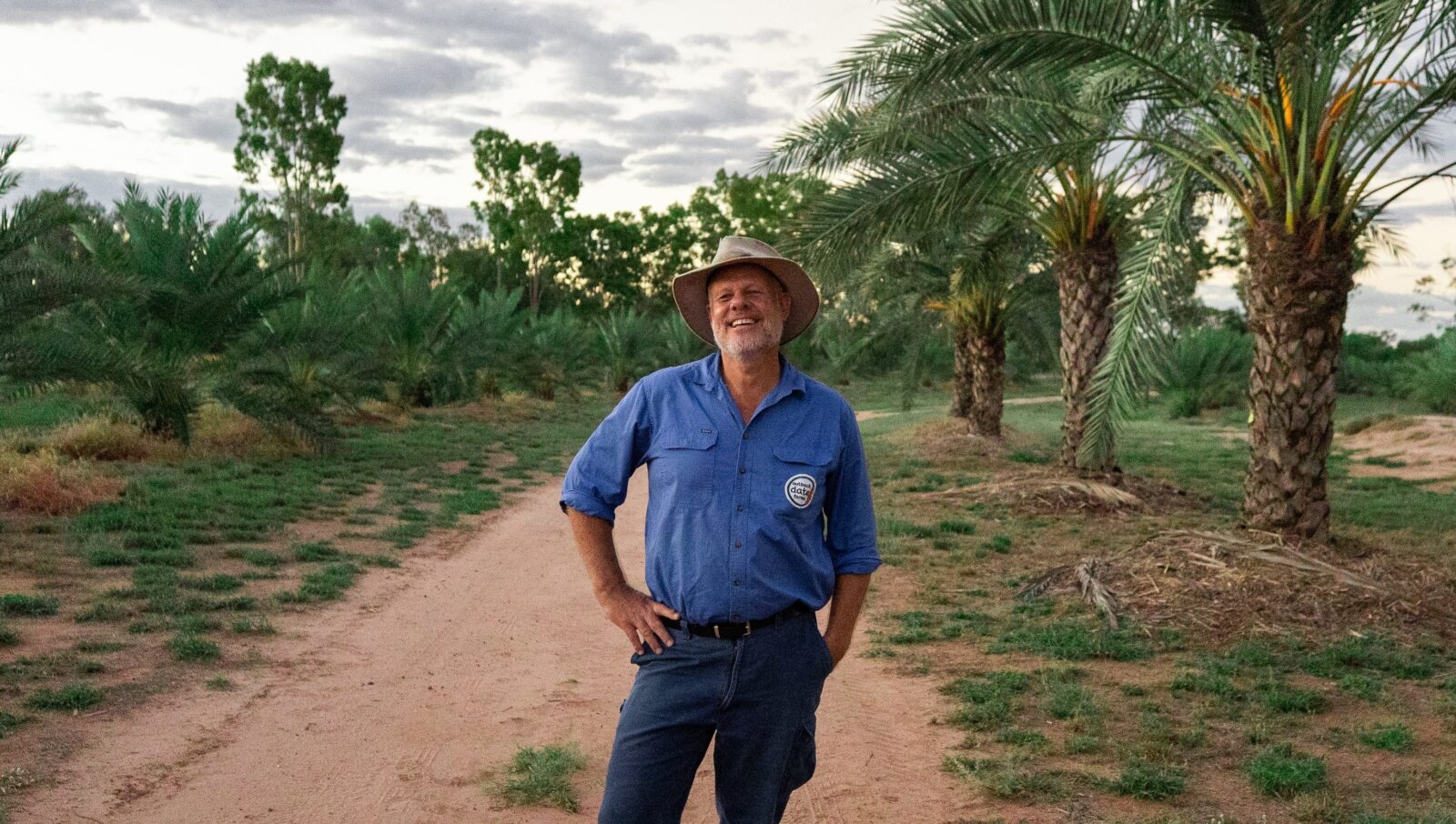 Outback Date Farms owner and tour guide standing between rows of palm trees