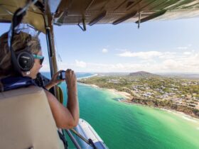 Seaplane passenger takes photos over Mt Coolum with doors off